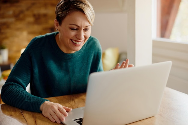 Happy woman using computer and having fun during video call at home