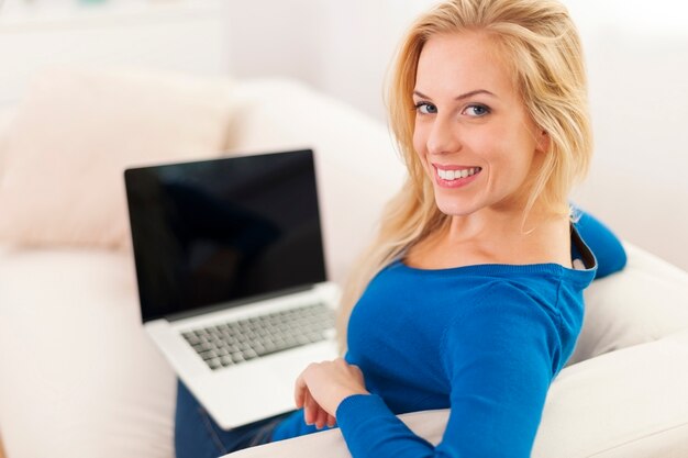 Счастливая женщина, использующая ноутбук дома