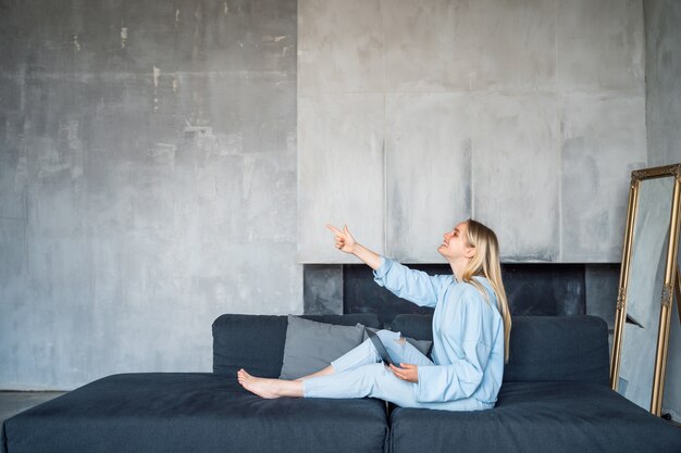 Happy woman using silver laptop while sitting on sofa