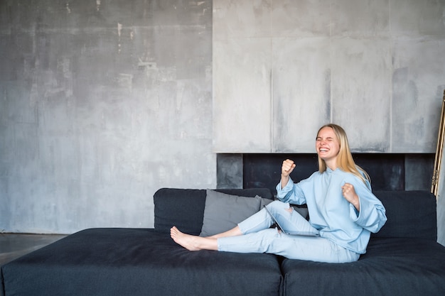 Happy woman using silver laptop while sitting on sofa