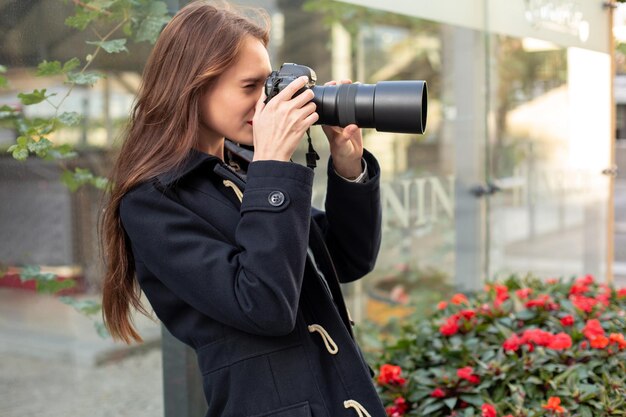 도시 거리에서 카메라로 사진을 찍는 휴가에 행복한 여자. 카메라와 함께 도시에서 즐거운 시간을 보내고 사진 작가의 여행 사진.