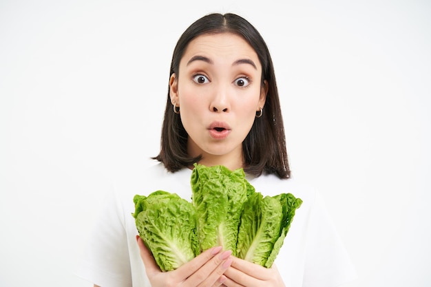 Free photo happy woman vegetarian looks at delicious lettuce likes eating fresh cabage vegan food white backgro