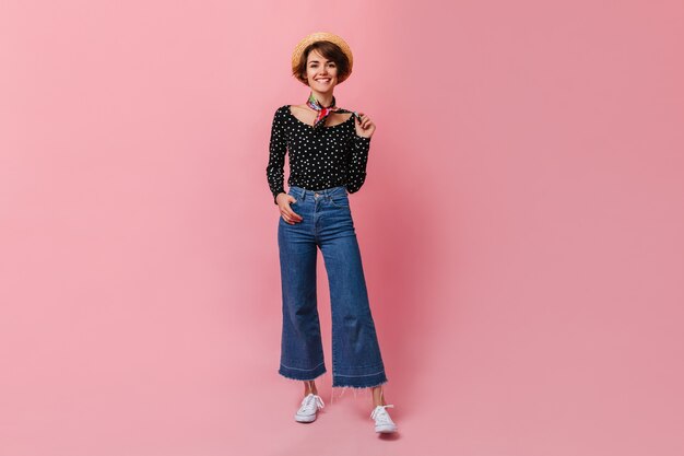 Happy woman in vintage jeans standing on pink wall