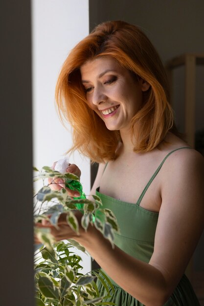 Счастливая женщина поливает растение средний план