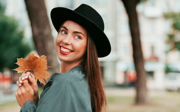 Foto gratuita felice donna che indossa un cappello nero mentre guarda lontano