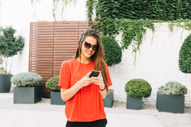Happy woman wearing sunglasses using cellphone