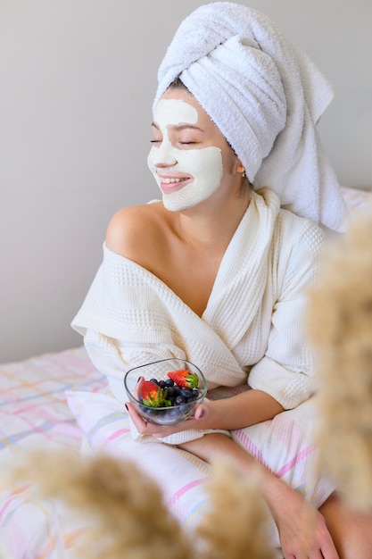 Happy woman wearing towel on head and face mask