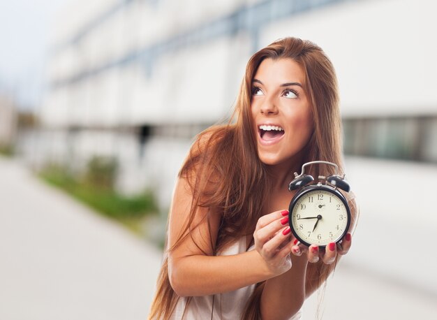 happy woman with alarm clock in the street
