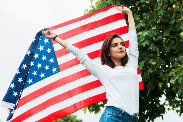 Счастливая женщина с американским флагом в природе