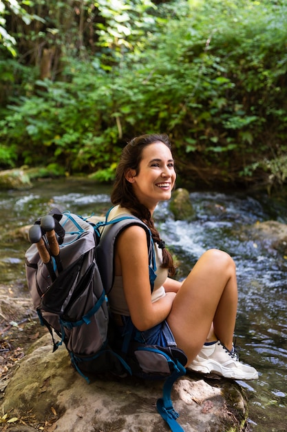 Foto gratuita donna felice con lo zaino che riposa mentre esplora la natura