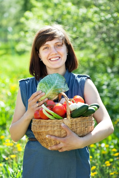 収穫した野菜のバスケットを持つ幸せな女性