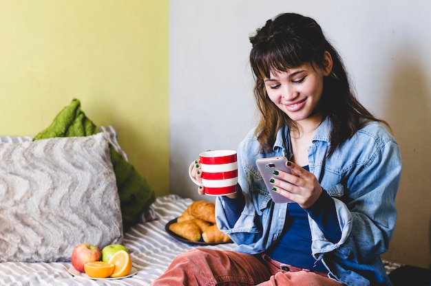 Foto gratuita donna felice con bevanda e telefono