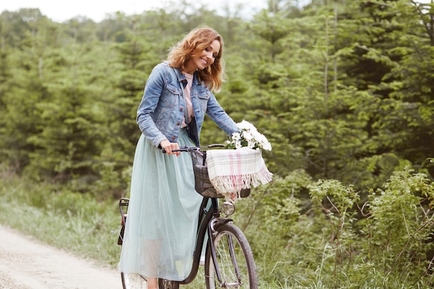 Счастливая женщина с велосипедом в парке