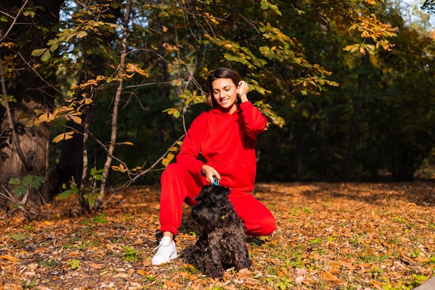 Happy woman with dog in park with autumnal leaves
