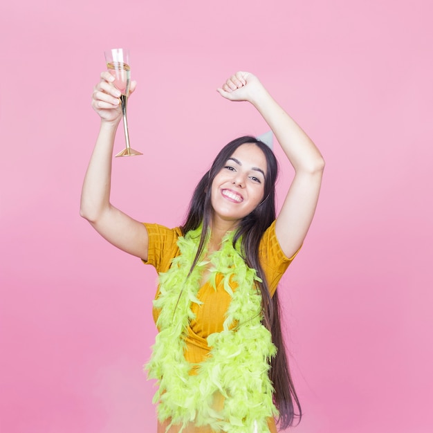 Бесплатное фото Счастливый женщина с напитком, подняв руки, танцуя на розовом фоне