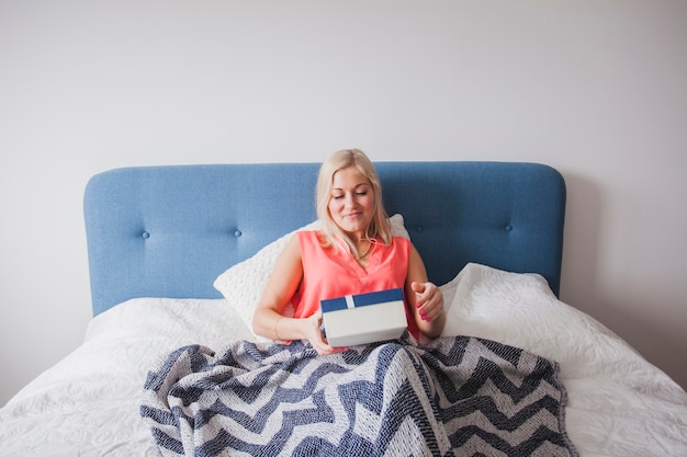 Happy woman with a gift on the bed