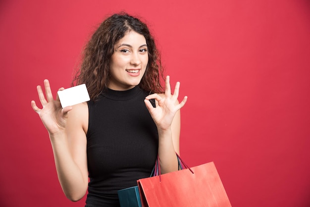 Happy woman with many of bags and bank card on red