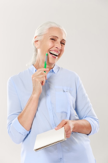 Free photo happy woman with pen and notebook looking and smiling