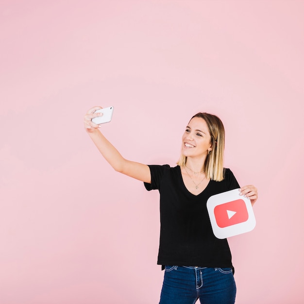 Happy woman with play icon taking selfie from mobile phone