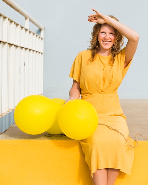 Foto gratuita donna felice con palloncini gialli