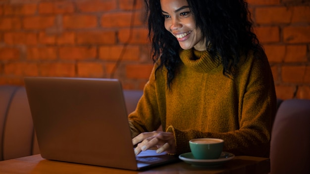 Счастливая женщина, работающая на своем ноутбуке в кафе