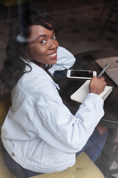 Free photo happy woman writing in notebook