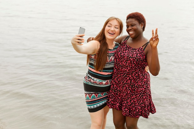 Foto gratuita donne felici in spiaggia prendendo selfie