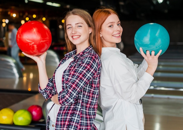 Happy women holding bowling balls