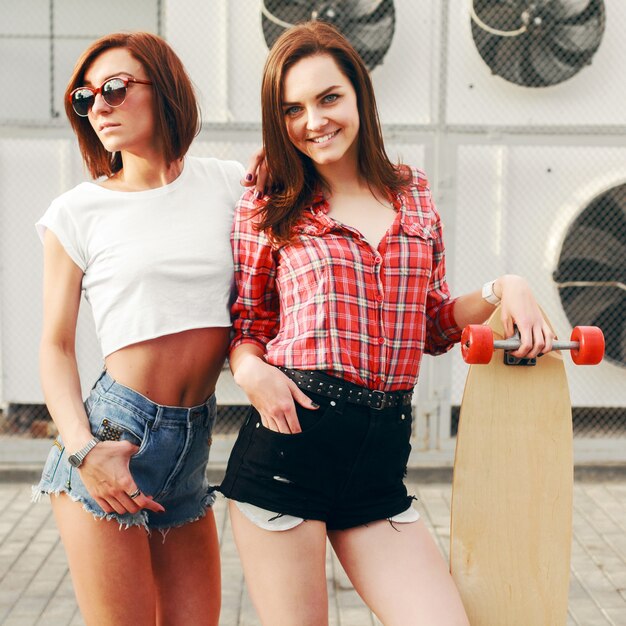 Happy women in shorts with a skateboard outdoors