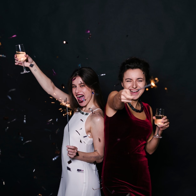 Free photo happy women with champagne glasses and sparklers