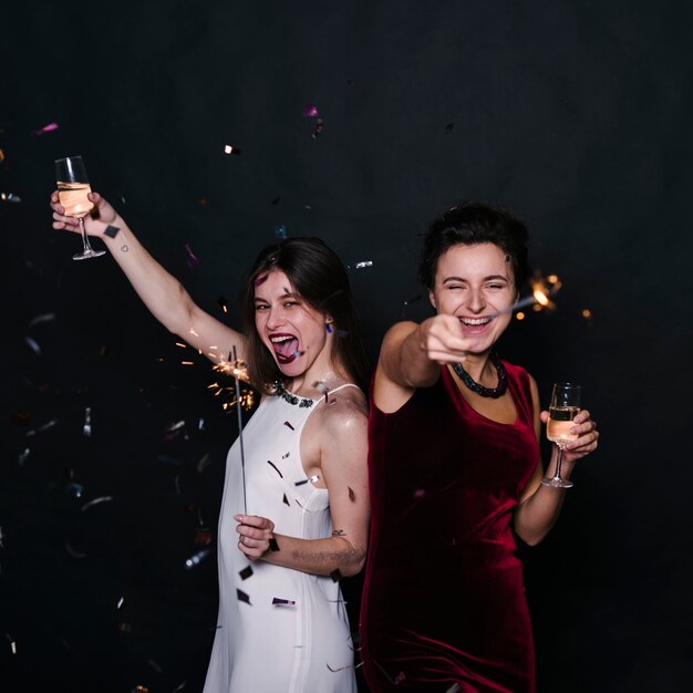 Happy women with champagne glasses and sparklers 