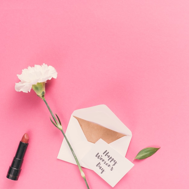 Счастливый женский день надпись с конвертом и цветок на розовом столе