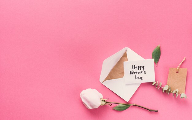 Happy Womens Day inscription with envelope and flower on table  