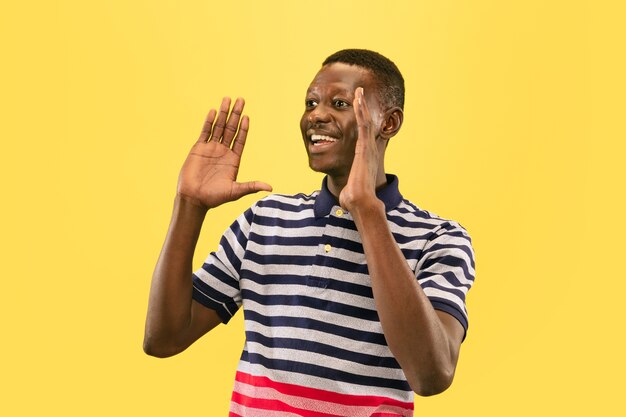 Счастливый молодой афро-американский человек, изолированные на желтом фоне студии, выражение лица. Красивый мужской портрет половинной длины. Понятие о человеческих эмоциях, выражении лица.