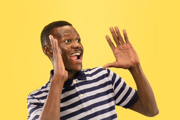 Happy young african-american man shouted loud isolated on yellow studio