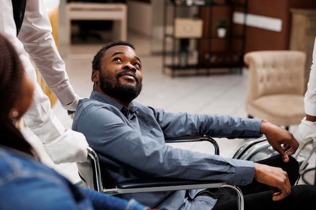 Free photo happy young african american man using wheelchair during travel, receiving help and assistance in wheelchair-friendly and accessible hotel. people with mobility impairment and traveling