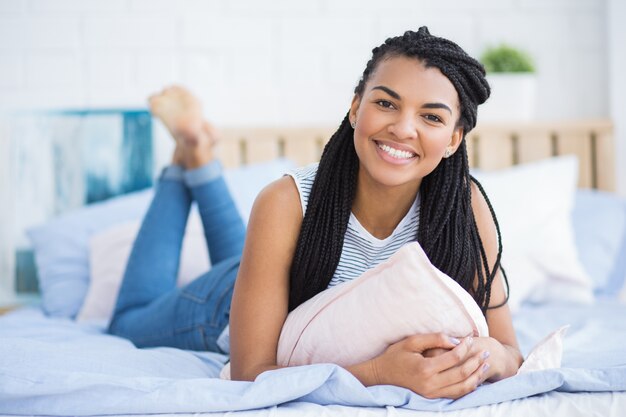 Happy young African-American woman resting in bed