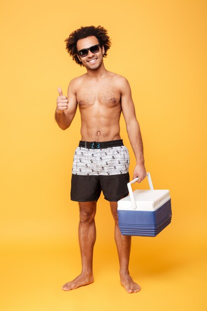 Happy young african man dressed in shorts showing thumbs up.