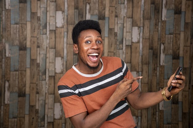 Happy young african man holding a cellphone