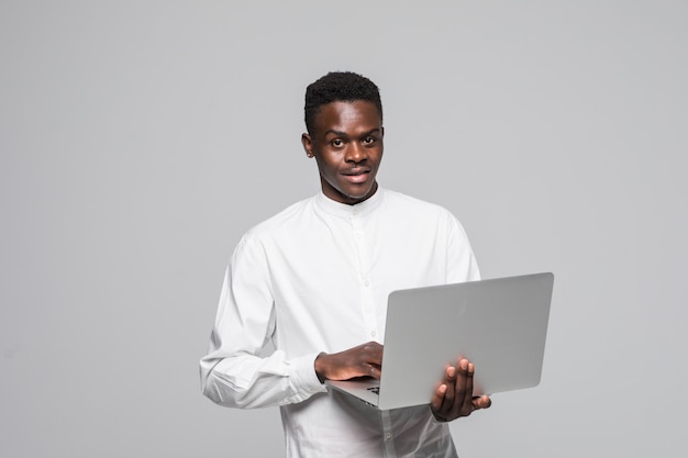 랩톱 컴퓨터를 사용하여 흰색 배경 위에 격리 된 서 행복 젊은 아프리카 남자.
