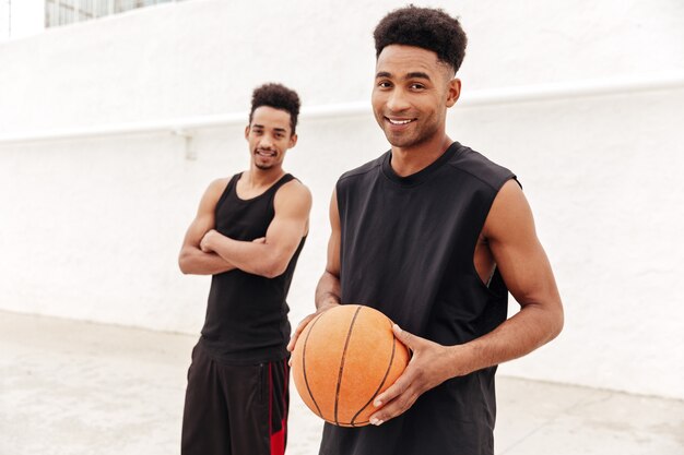 Happy young african sports men with basketball