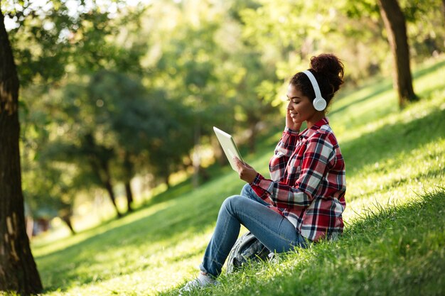 Happy young african woman sitting outdoors in park.