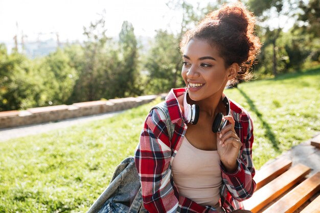 Happy young african woman sitting outdoors in park.