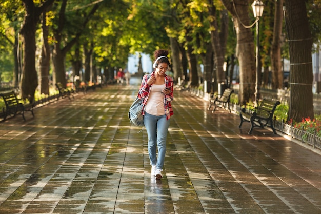 Happy young african woman walking outdoors in park.