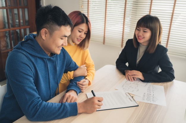 Happy young asian couple and realtor agent