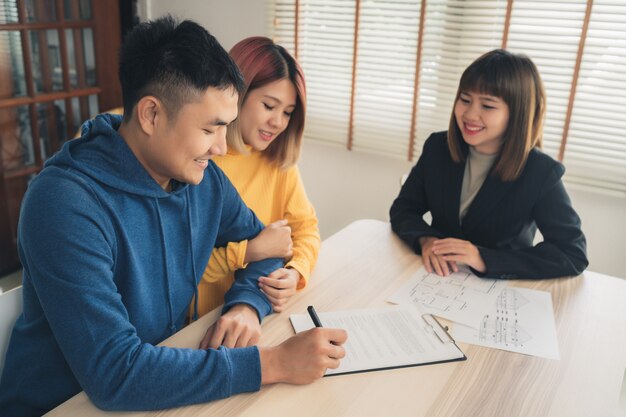 Happy young Asian couple and realtor agent