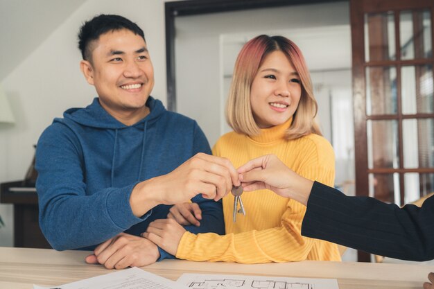 Happy young asian couple and realtor agent