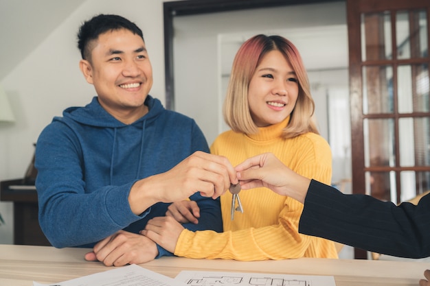 Happy young Asian couple and realtor agent