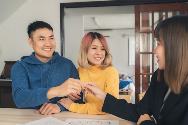 행복 한 젊은 아시아 부부와 부동산 에이전트