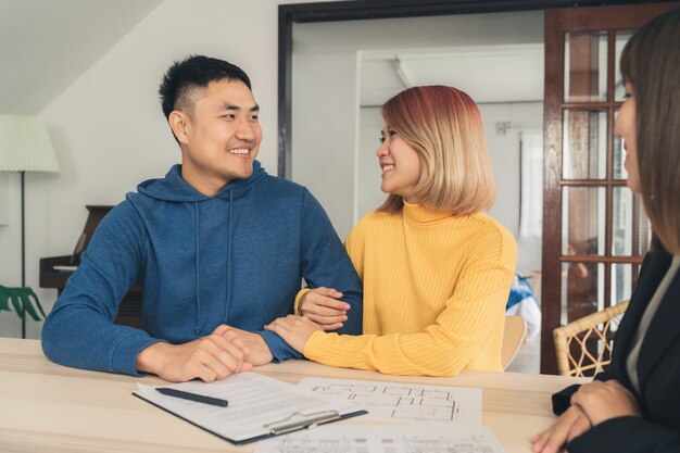 Happy young Asian couple and realtor agent